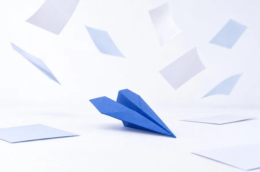 Papierflieger zwischen herumwirbelnden Papierblättern